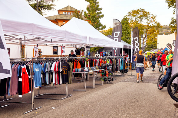 I gazebo promozionali bianche fungono come gazebo di vendita in occasione di un evento. Sotto i gazebo sono appese diverse magliette.