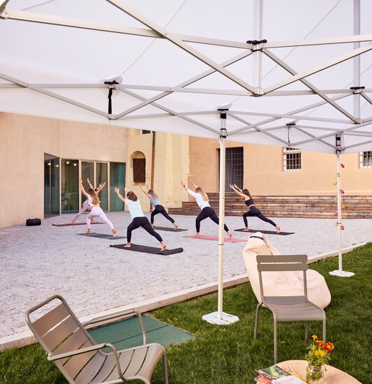 Gazebo Ecotent bianco 6x4m su gairdino davanti alla biblioteca di Bressanone utilizzato outdoor per corso di yoga rpara l'area relax dal sole