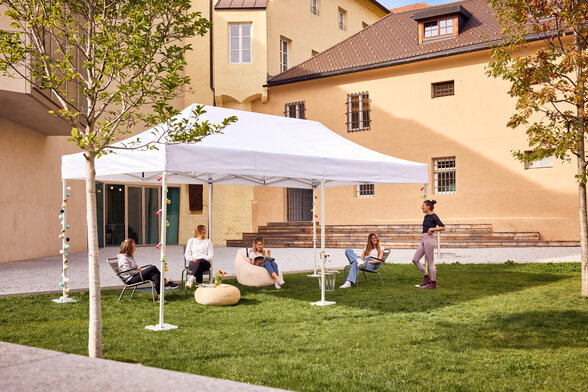 Der 6x3 m große Faltpavillon dient als Outdoor-Überdachung einer Bibliothek. Darunter sitzen Jugendliche.