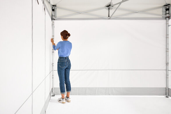 La donna assembla le 2 pareti laterali chiuse del gazebo pieghevole.