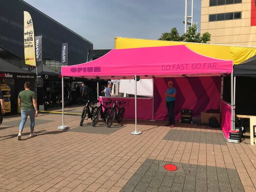 Gazebo pieghevole fuxia 6x3 personalizzato con logo Opium e diversi teli laterali all'Eurobike in Svizzera fa da stand delle biciclette.