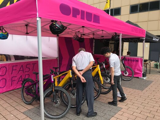 Gazebo pieghevole fuxia 6x3 personalizzato con logo Opium e diversi teli laterali all'Eurobike in Svizzera fa da stand delle biciclette mentre due uomini guardano.