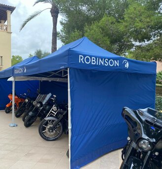 Due gazebo blu 3x4,5 con grondaia e teli laterali utilizzati come garage moto personalizzati con logo bianco Robinson.