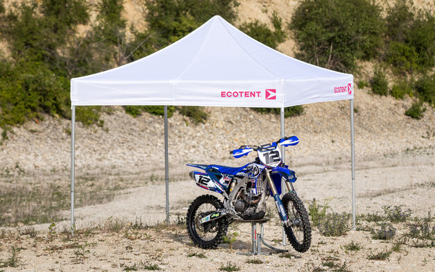 Gazebo bianco 3x3 m con logo Ecotent fuxia copre una moto da motocross blu nel deserto